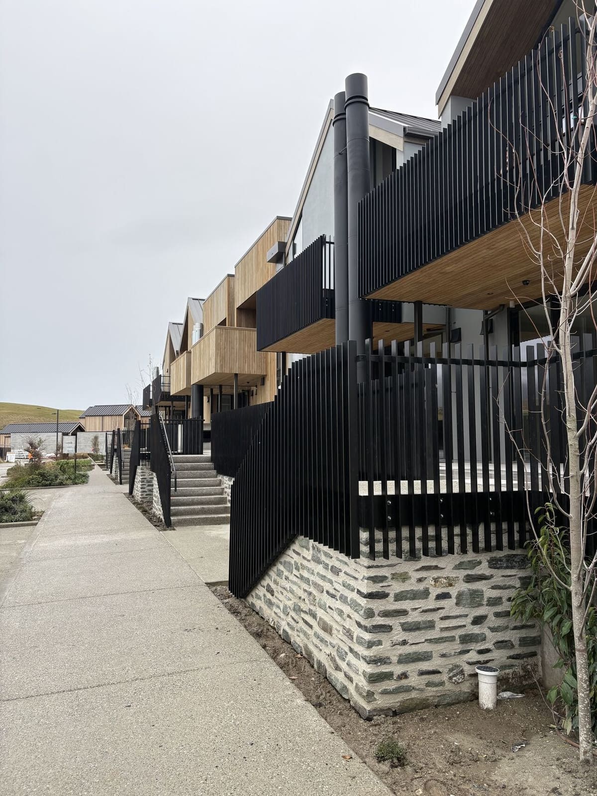 Black aluminium slat balustrade above a schist stone wall, Arthurs Point