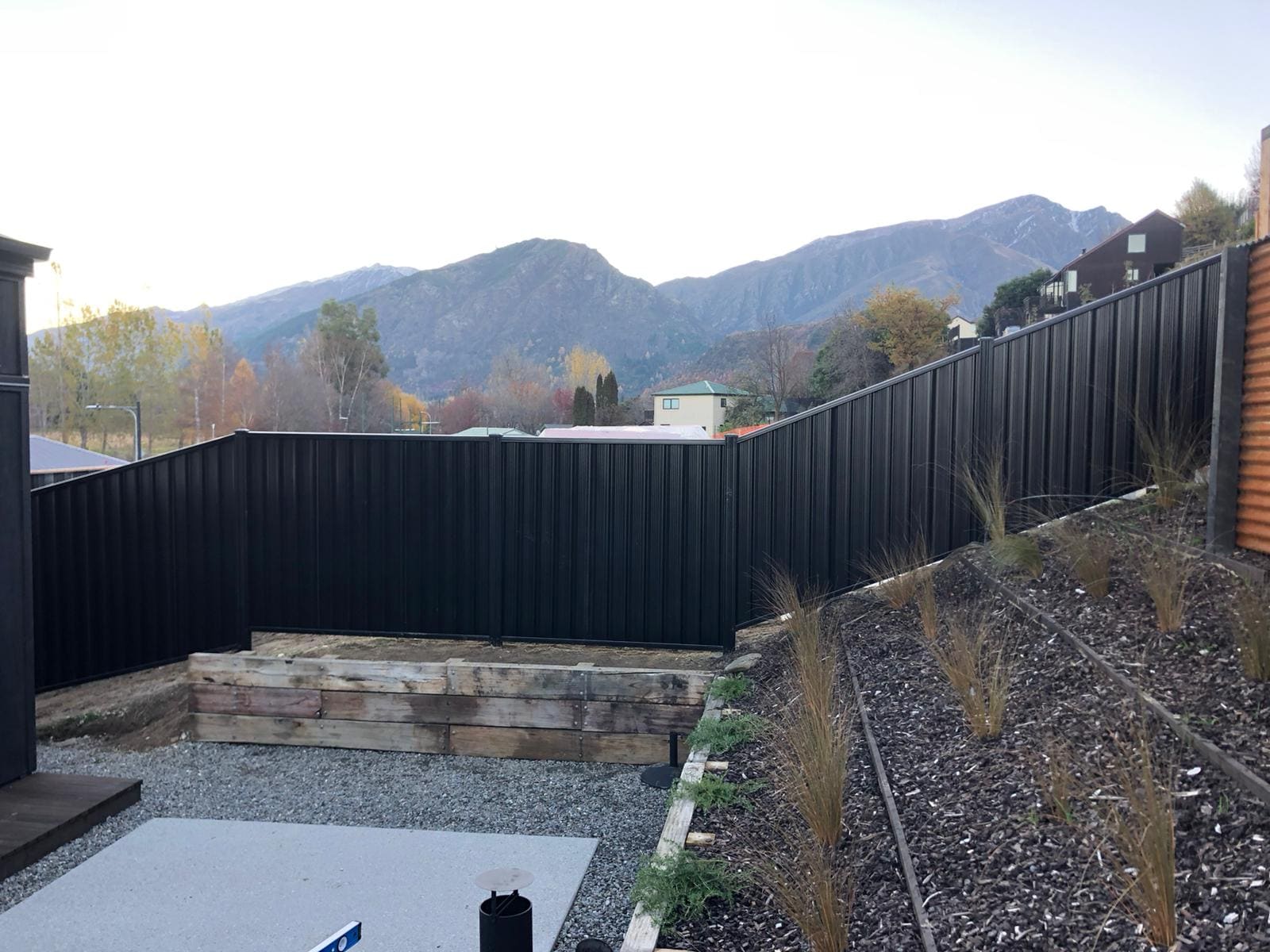 Black colour steel panel fencing around a new Queenstown home with mountains behind