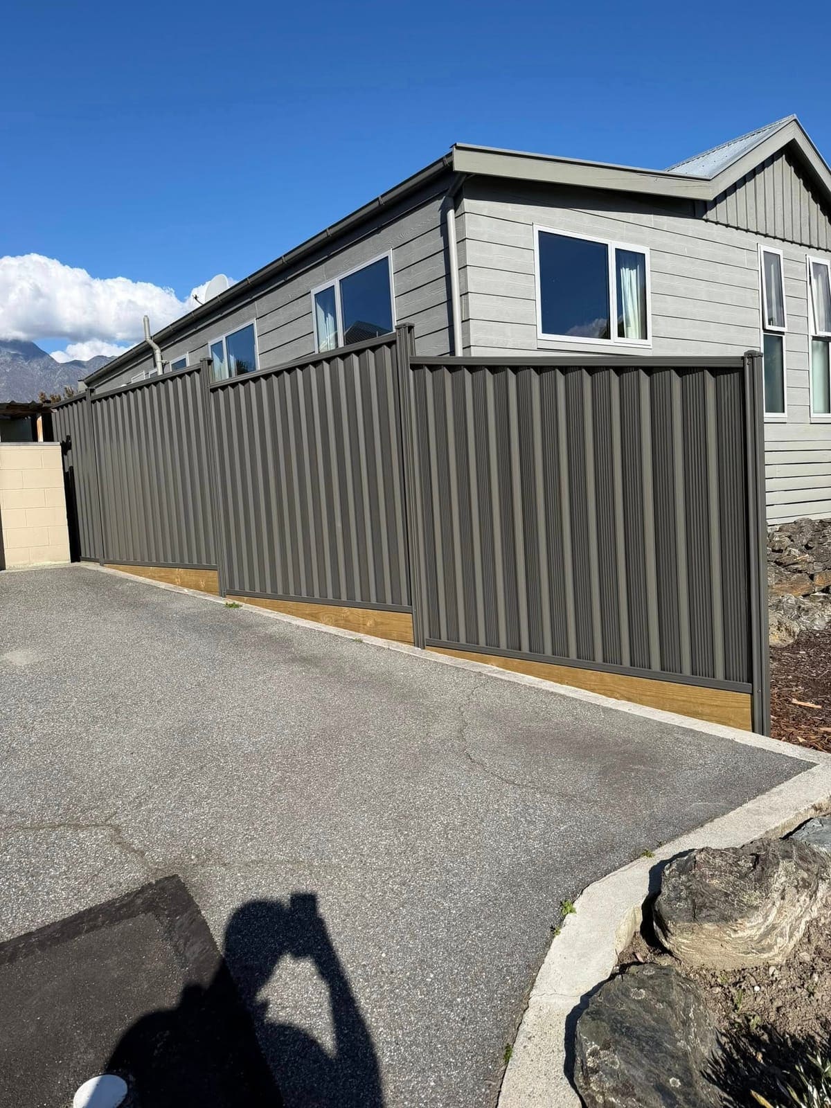 Dark colour steel panel fencing along a lawn boundary, Queenstown