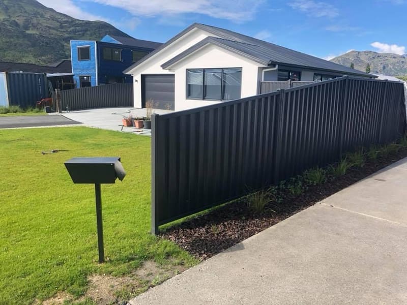 Long run of dark colour panel fencing on a Queenstown boundary