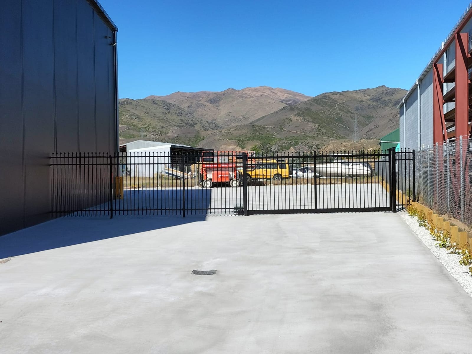 Black sliding automatic gate at a commercial yard with Queenstown mountains behind