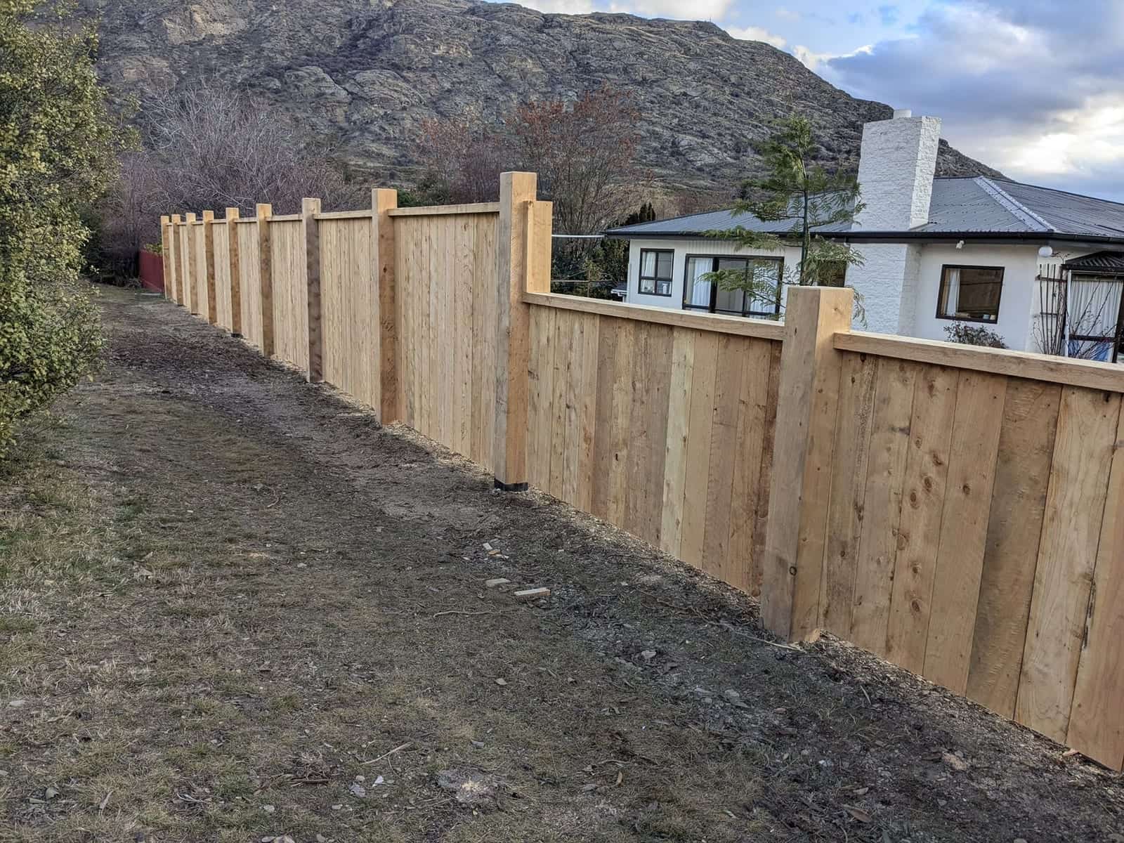 Long macrocarpa fence run with dramatic mountain backdrop, Queenstown
