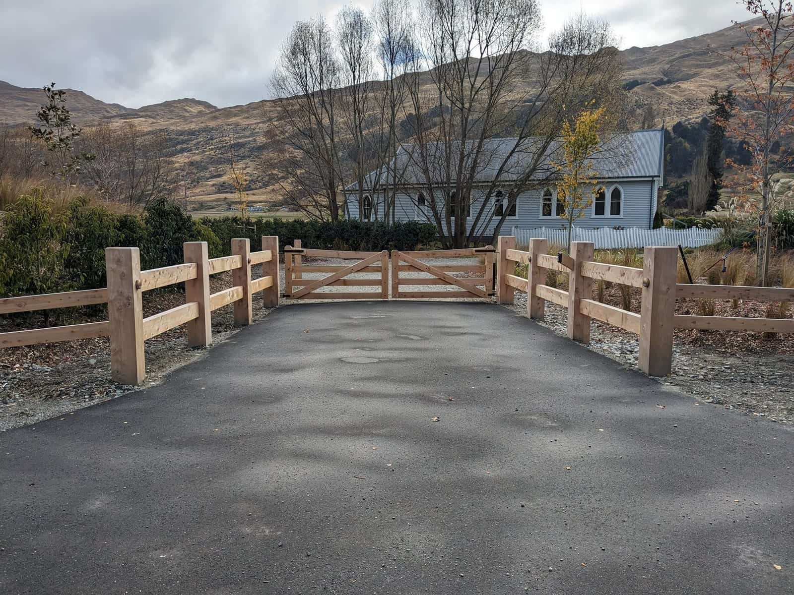 Macrocarpa double gate with old church and valley views, Central Otago