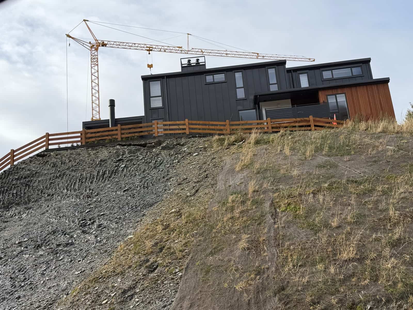 Macrocarpa post and rail fence along a hillside new build, Queenstown