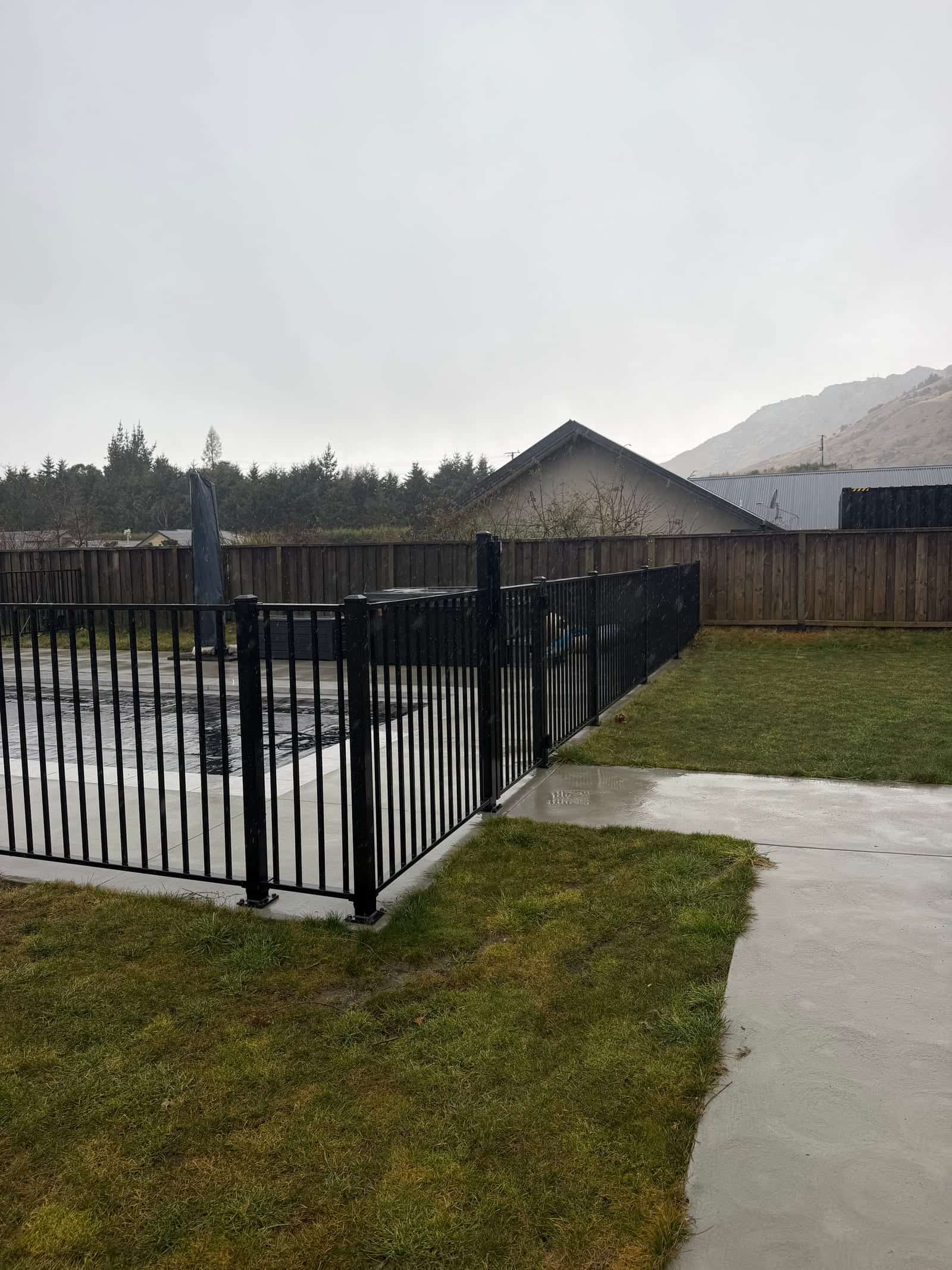 Black tubular steel pool fence along a lawn boundary, Queenstown