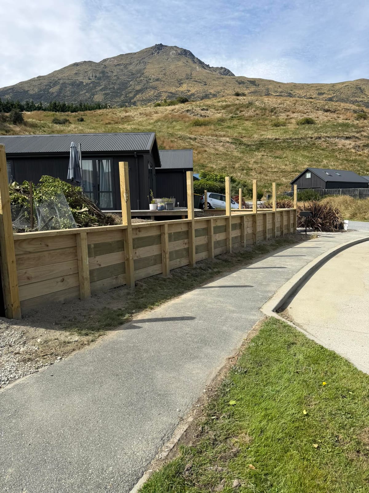 Timber retaining wall running alongside a footpath below a new Queenstown home