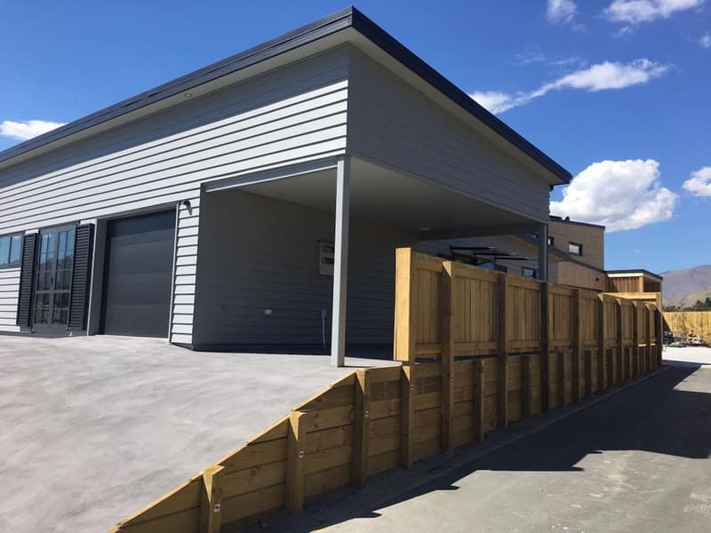 Timber sleeper retaining wall beside a new home and carport, Queenstown