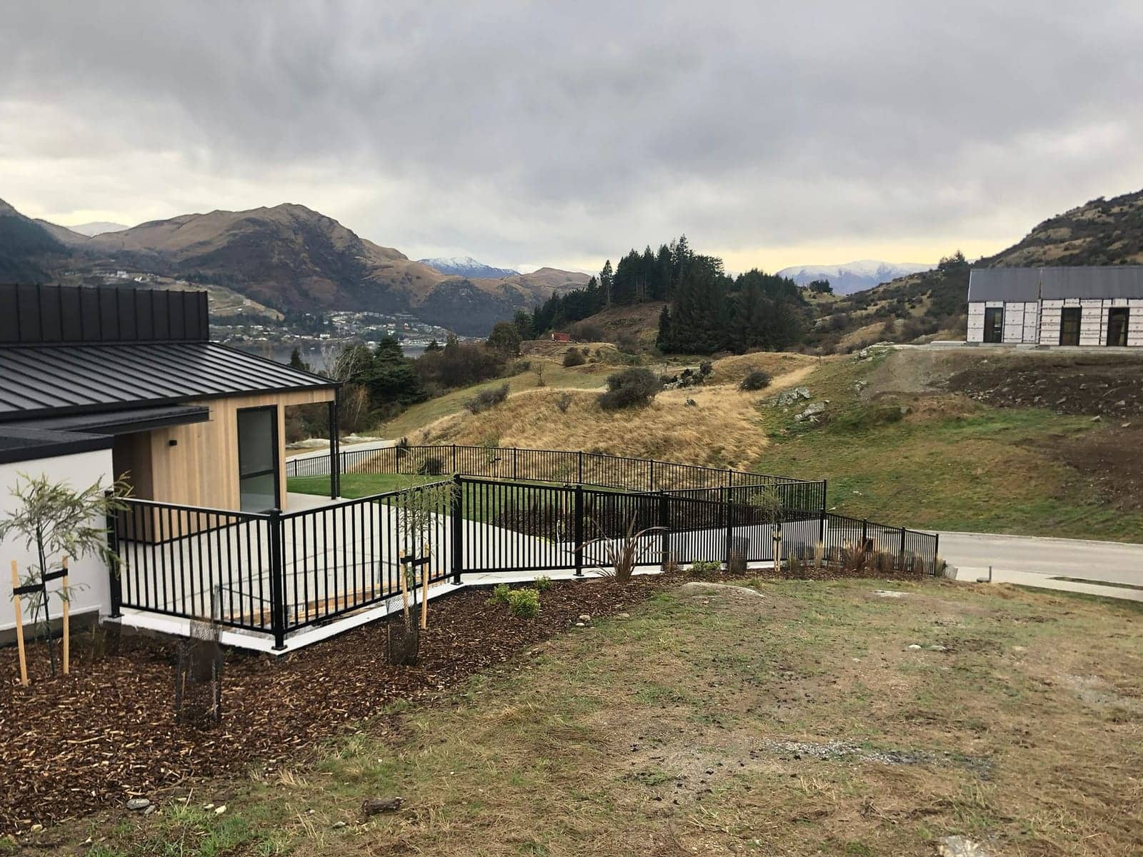 Black tubular steel fencing around a raised deck with lake and mountain views, Queenstown