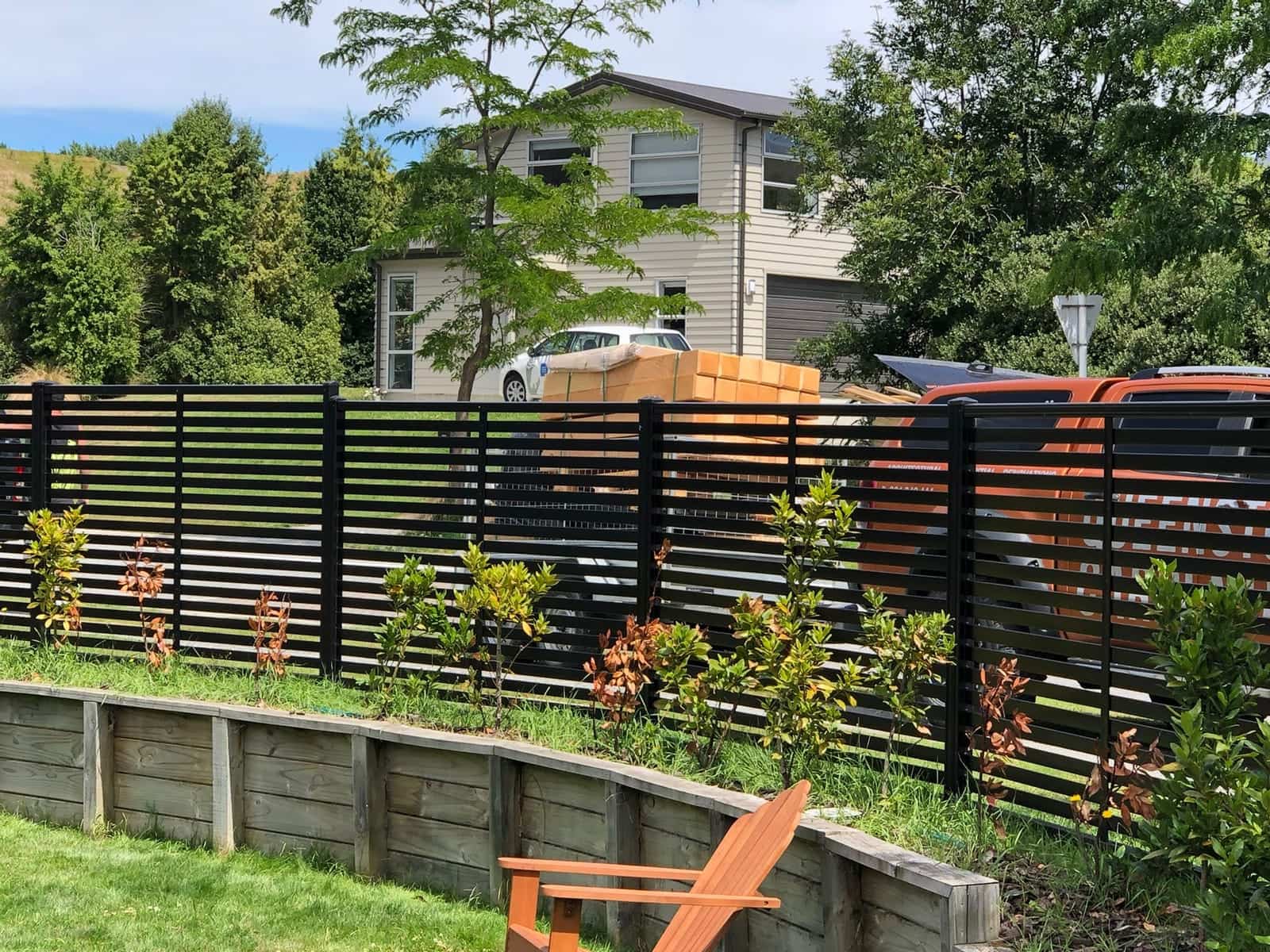 Black horizontal slat fence with cedar detailing beside a garden, Queenstown