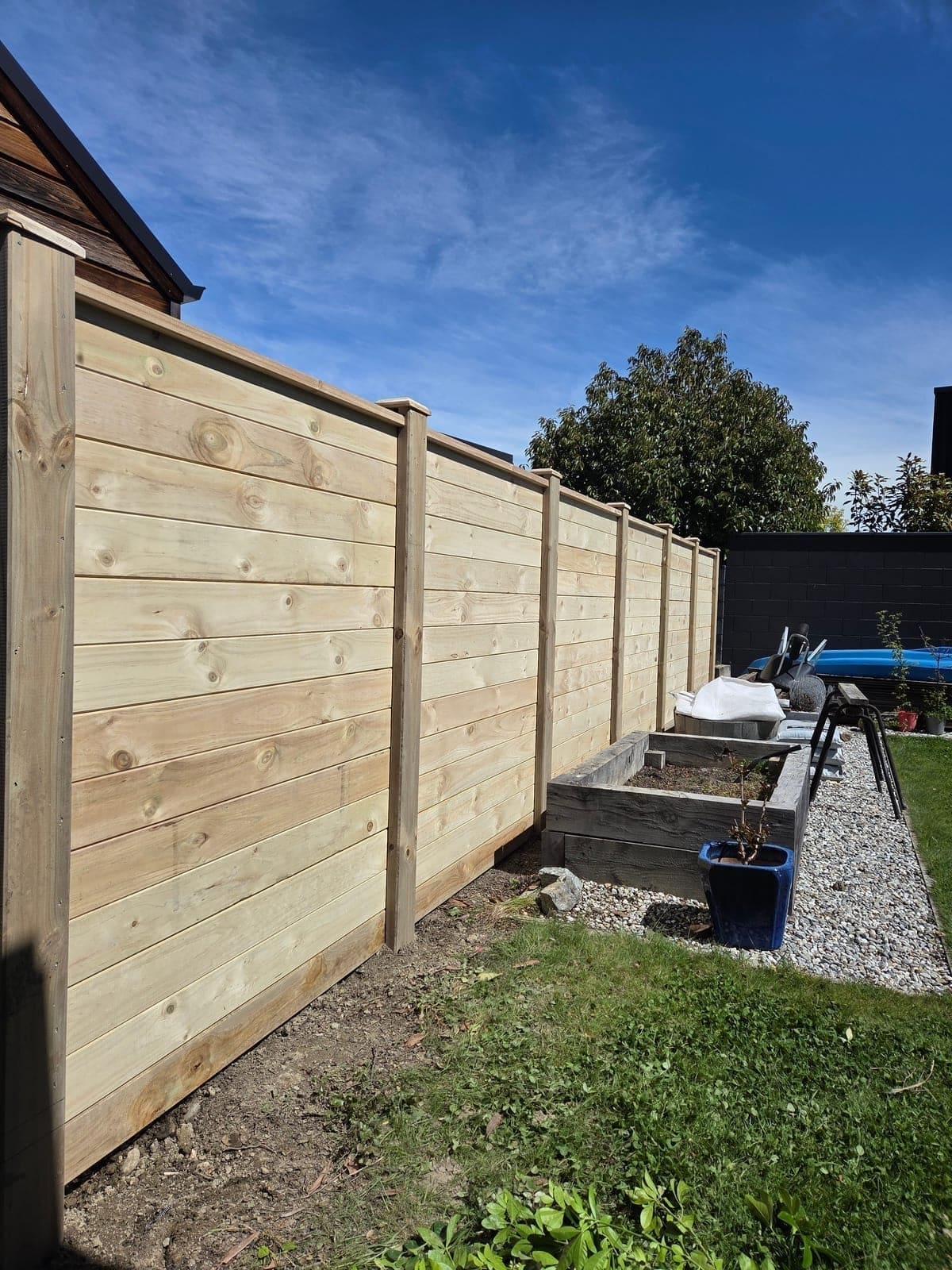 Horizontal timber paling fence with capped posts beside a Queenstown garden